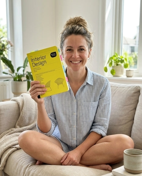 Holding up the yellow Interior Design book on a sofa