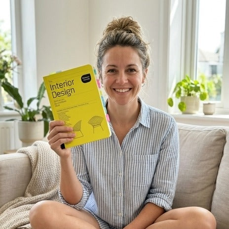 Holding up the yellow Interior Design book on a sofa